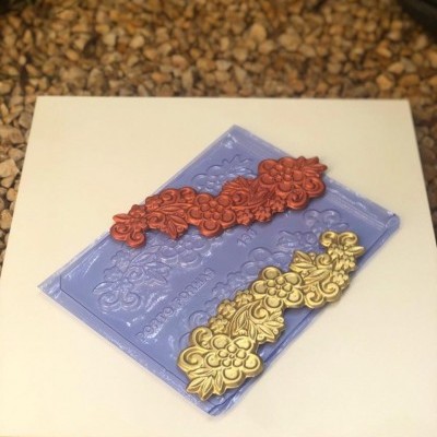 Molde de silicone azul com aplicações decorativas vermelha e dourada em padrão floral
