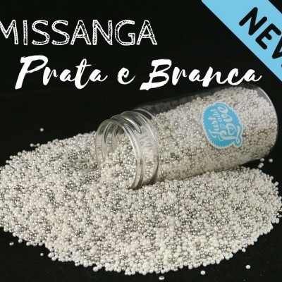 Frasco aberto com missangas prata e branca espalhadas sobre fundo preto