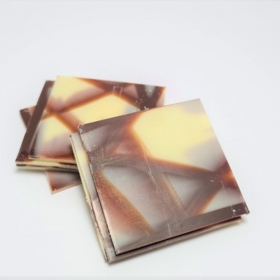 Azulejos quadrados com padrão marmoreado castanho e amarelo sobre fundo branco