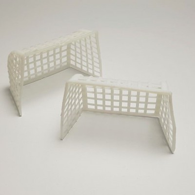 Duas pequenas balizas de futebol brancas em plástico sobre superfície branca