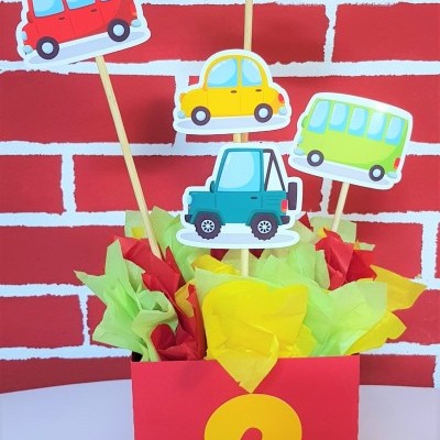 Arranjo decorativo com carros de papel, caixa vermelha e número 2 amarelo