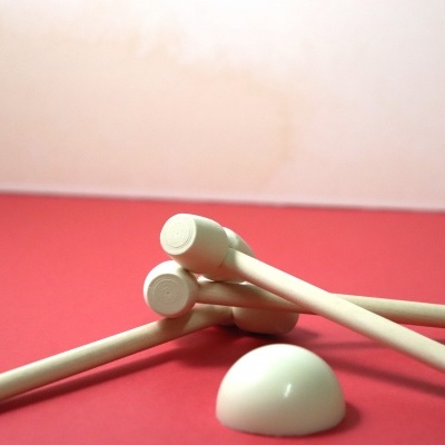 Varetas de madeira com pontas e peça circular branca sobre fundo vermelho