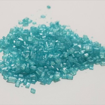 Grânulos pequenos de plástico azul translúcido sobre superfície branca