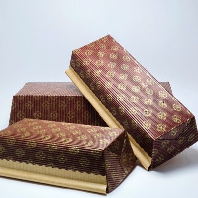 Três caixas de papelão castanhas com padrão dourado e base em papel kraft