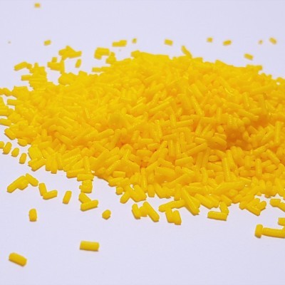 Pequenas granulas amarelas cilíndricas sobre superfície branca