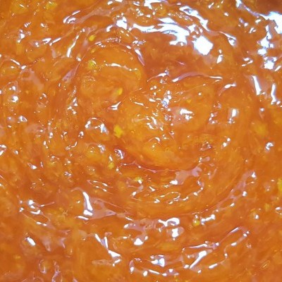 Geleia ou doce laranja brilhante com textura granulada e translúcida em close-up