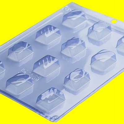 Molde plástico transparente com cavidades em forma de sacos de mão sobre fundo amarelo