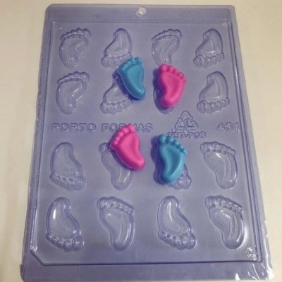 Molde de confeitaria azul com cavidades em forma de pé e doces coloridos