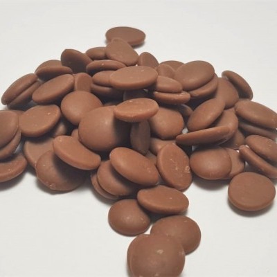 Montinho de pequenos discos de chocolate castanho claro sobre superfície branca.