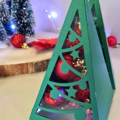 Caixas triangulares verdes com decoração natalícia e bolas vermelhas dentro