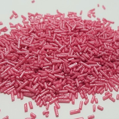 Confeitos cilíndricos rosa brilhantes sobre superfície branca