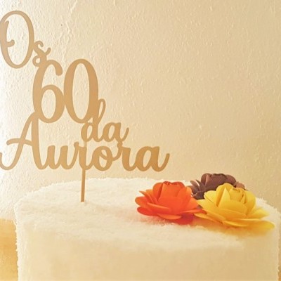 Bolo branco com decoração de flores coloridas e topo de madeira dourada com texto