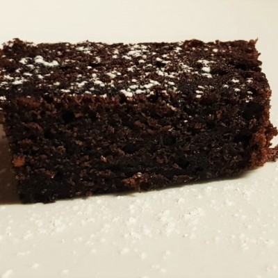 Bolo quadrado de chocolate polvilhado com açúcar em pó sobre prato branco