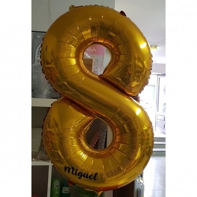 Balão dourado número 8 com texto Miguel em ambiente interior