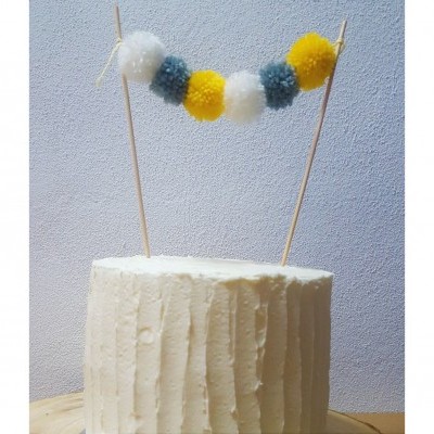 Bolo branco decorado com pompons coloridos suspensos por palitos