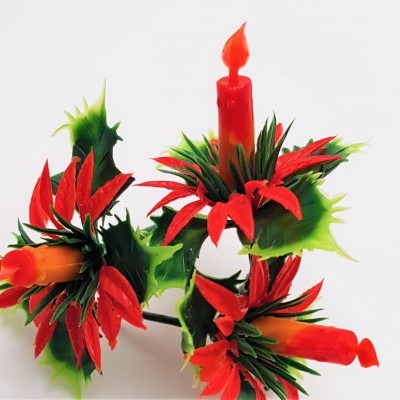 Vela vermelha decorativa em forma de flor com pétalas vermelhas e verdes.