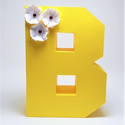 Letra decorativa B amarela com flores brancas