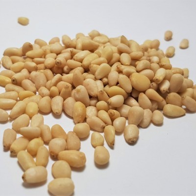 Pinhões crus amarelados sobre superfície branca