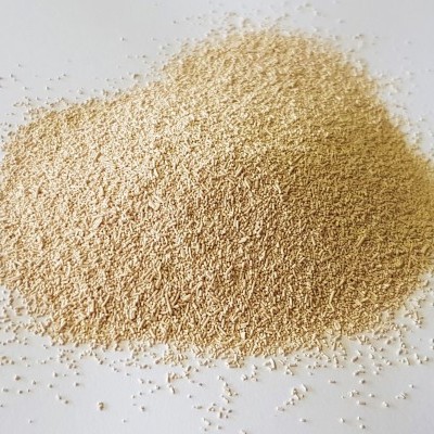 Montinho de fermento seco instantâneo granulado bege claro sobre fundo branco