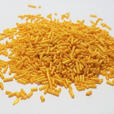 Confeitos amarelos em pequenos cilindros sobre superfície branca