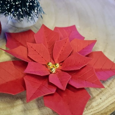 Flor decorativa vermelha de Natal com esferas douradas em base de madeira rústica