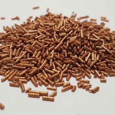 Confeitos cilíndricos dourados metálicos sobre superfície branca