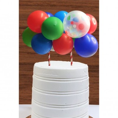 Bolo branco com balões coloridos no topo, sobre superfície branca e fundo de madeira.