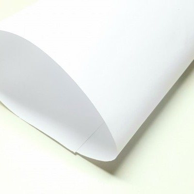 Folha de papel branca ligeiramente enrolada sobre superfície clara