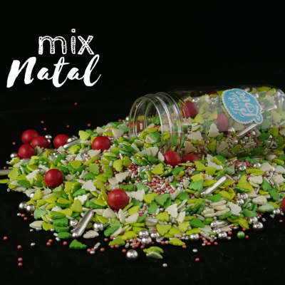 Mix de confeitos coloridos para Natal em recipiente tombado sobre fundo preto.