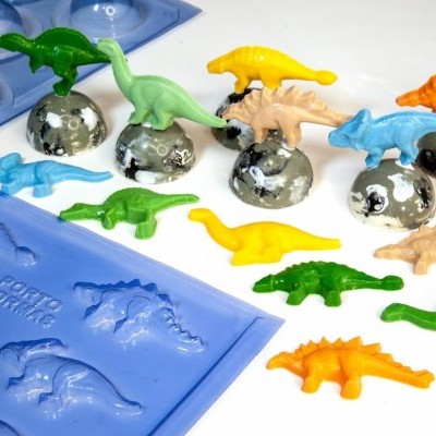 Figuras de dinossauros coloridos em bases prateadas com moldes de silicone azul ao lado