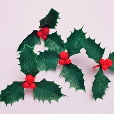 Ramos artificiais de azevinho verde com frutos vermelhos sobre fundo branco