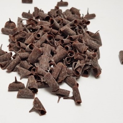 Pedaços de chocolate escuro enrolados sobre superfície branca