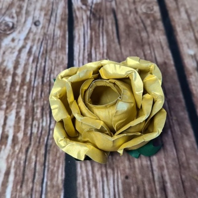 Flor de papel amarela sobre superfície de madeira rústica