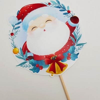 Cartaz de papel com desenho de Pai Natal sorridente e decoração natalícia em pau de madeira