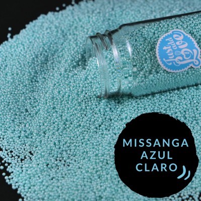 Missangas azul claro derramadas de frasco de vidro sobre fundo preto