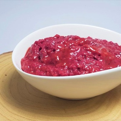 Purê vermelho em recipiente branco sobre fatia de madeira