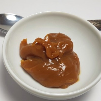 Taça com doce castanho e colher metálica com cabo decorado