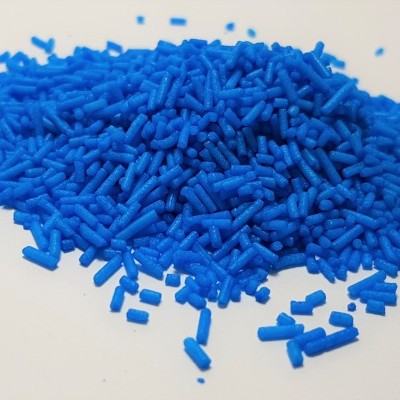 Grânulos plásticos azuis cilíndricos curtos sobre uma superfície branca