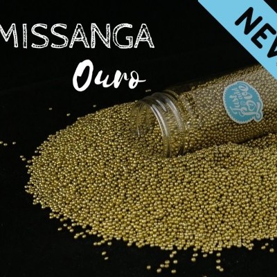 Frasco de vidro com missangas douradas dispersas e texto informativo