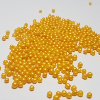 Contas esféricas amarelas brilhantes dispersas em superfície branca