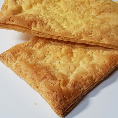 Dois quadrados de massa folhada dourada com textura crocante sobre fundo branco