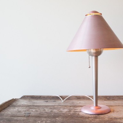 Candeeiro de mesa com cúpula rosa sobre mesa de madeira