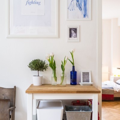 Móvel com flores e quadros decorativos na parede branca