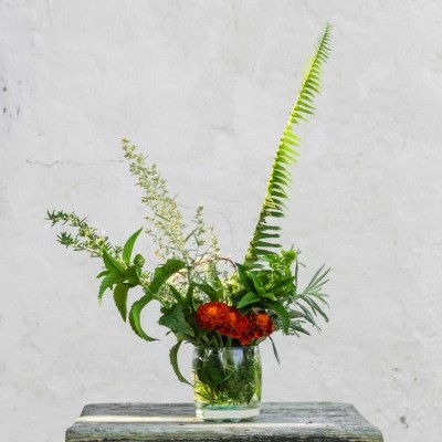 Arranjo floral em vaso de vidro sobre banco de madeira envelhecido