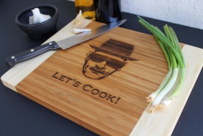 Tábua de cortar de madeira com gravação LET'S COOK!, faca, cebolas verdes, alho e molhador de azeite