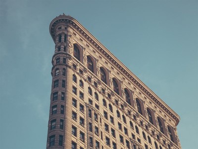 Edifício triangular de tijolo com janelas arqueadas sob céu azul