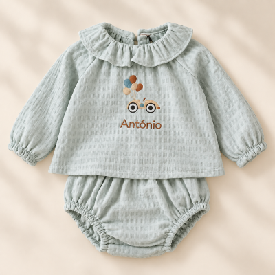 Conjunto de bebé azul claro com camisola com folho e estampagem de carrinho e balões e cueiros elásticos.