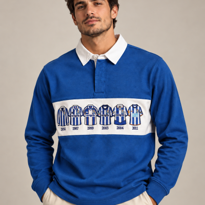 Homem veste sweatshirt azul com gola branca e estampagem de camisolas de futebol azuis e brancas com anos e marcas visíveis