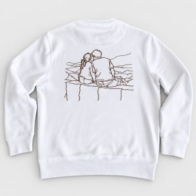 Sweatshirt branca com bordado de casal sentado de costas num muro.