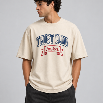 HOMEM a vestir uma t-shirt bege com texto TRUST CLUB e Juro, Joca.